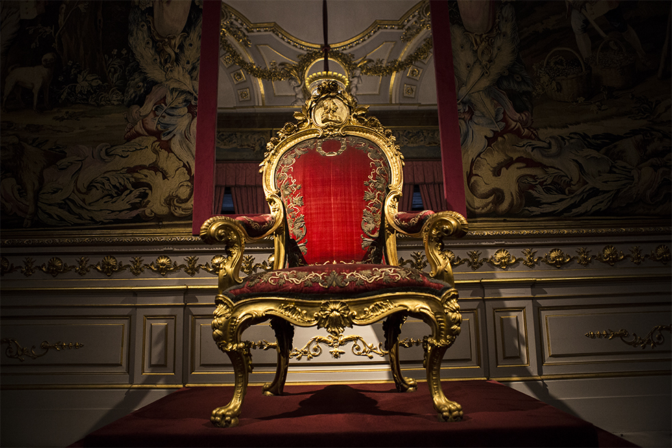 Trono de Carlos III, este sillón era el que el monarca Carlos III utilizaba en el Salón de los Reinos del Palacio Real de Madrid. Se trata de una silla, con maderas talladas y doradas, cubierta de terciopelo carmesí con sobrepuesto de oro y en cuyo copete está tallado el busto del rey.